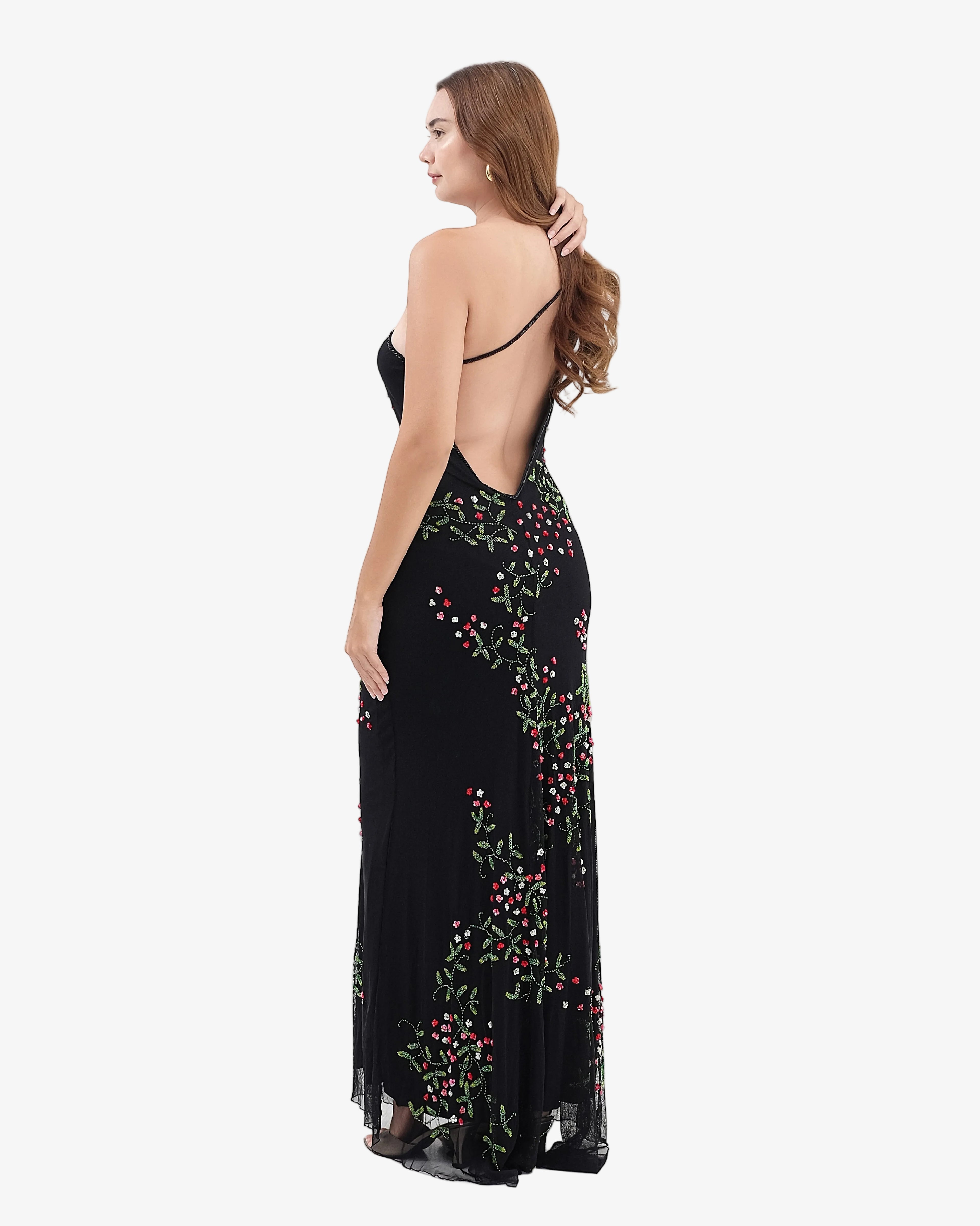 Woman wearing a black evening gown with floral embroidery on a white background