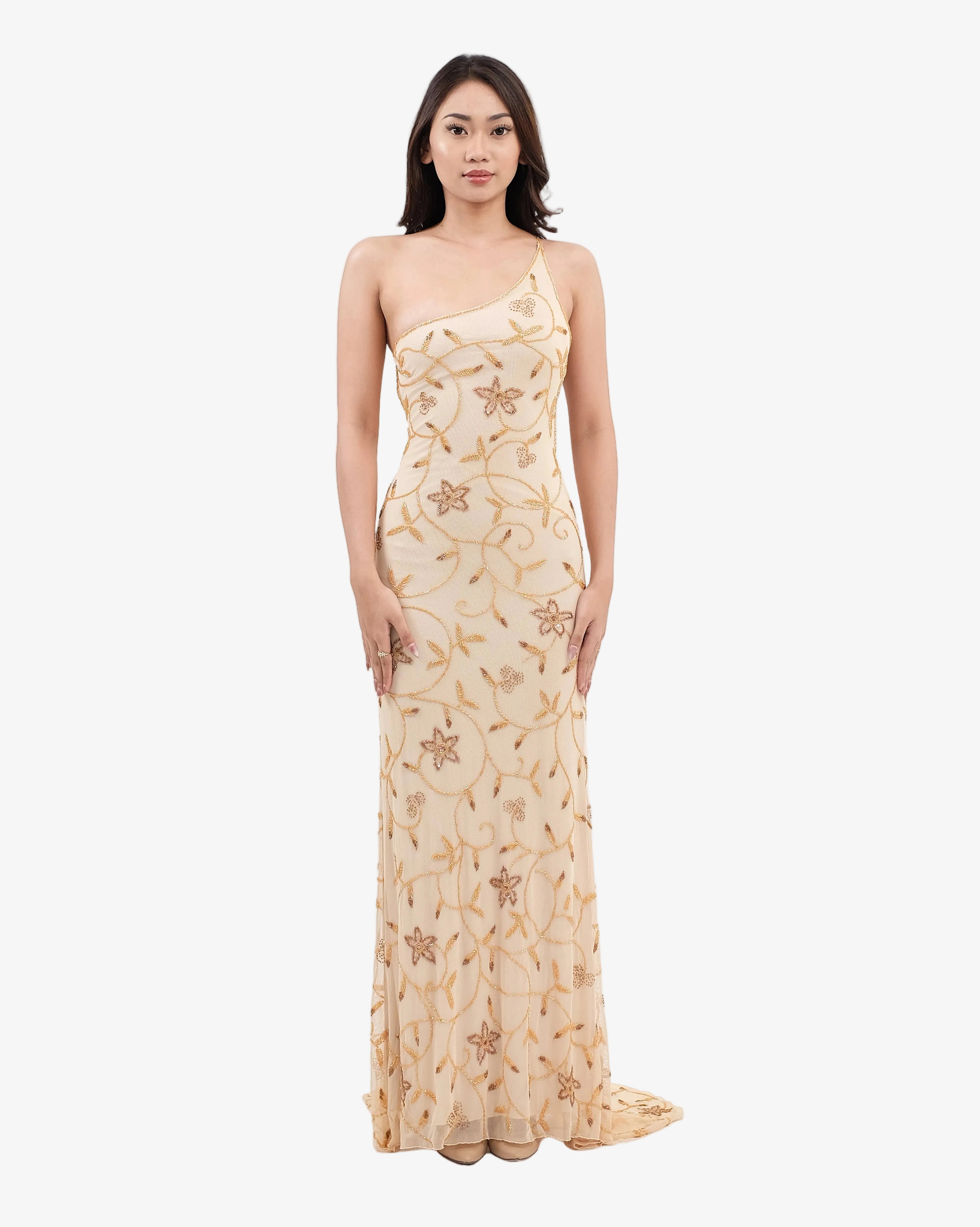 Woman wearing a beige strapless gown with floral patterns on a white background