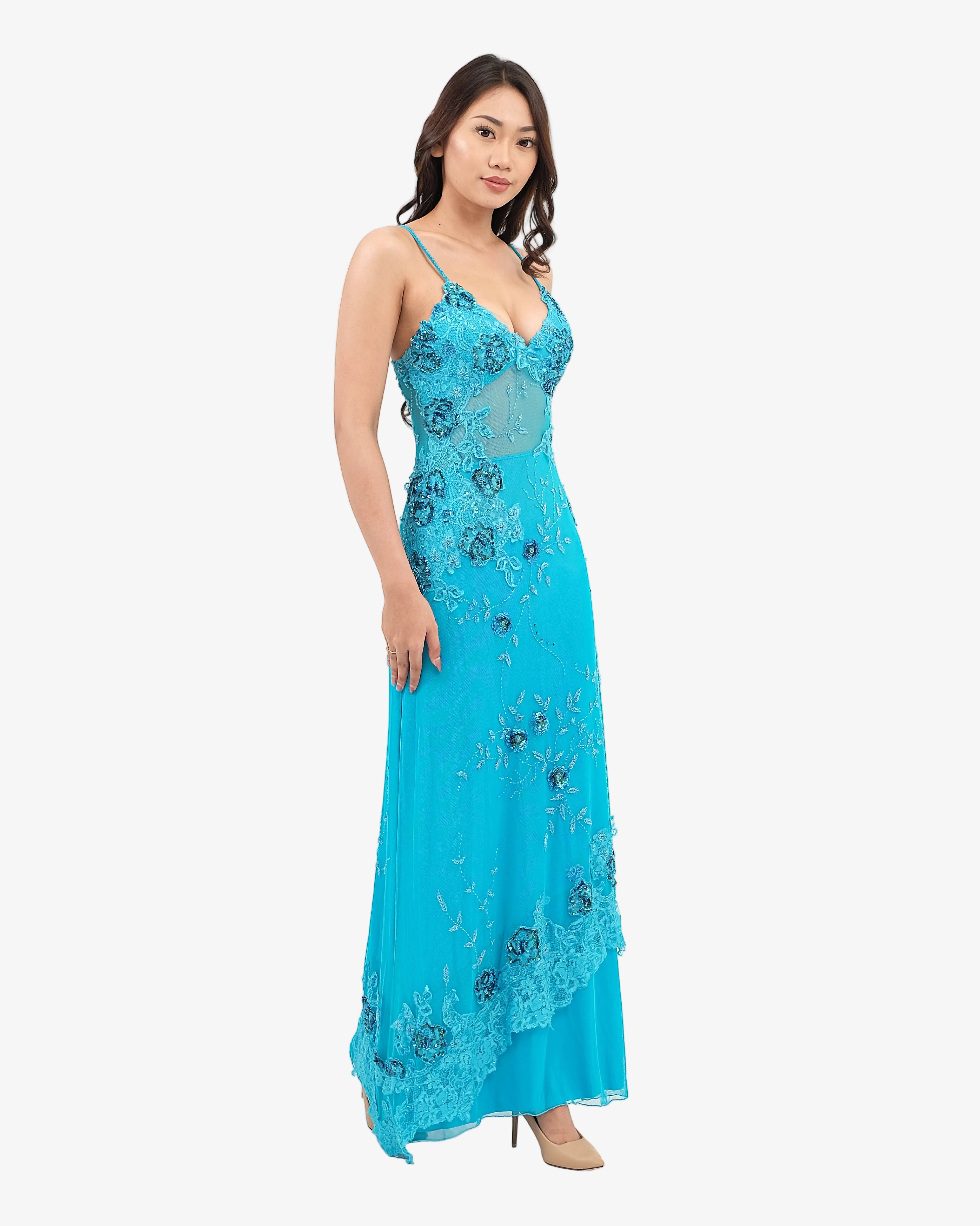 Woman wearing a Turquoise evening gown with floral embroidery on a white background