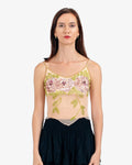Woman wearing a floral embroidered top with a plain background